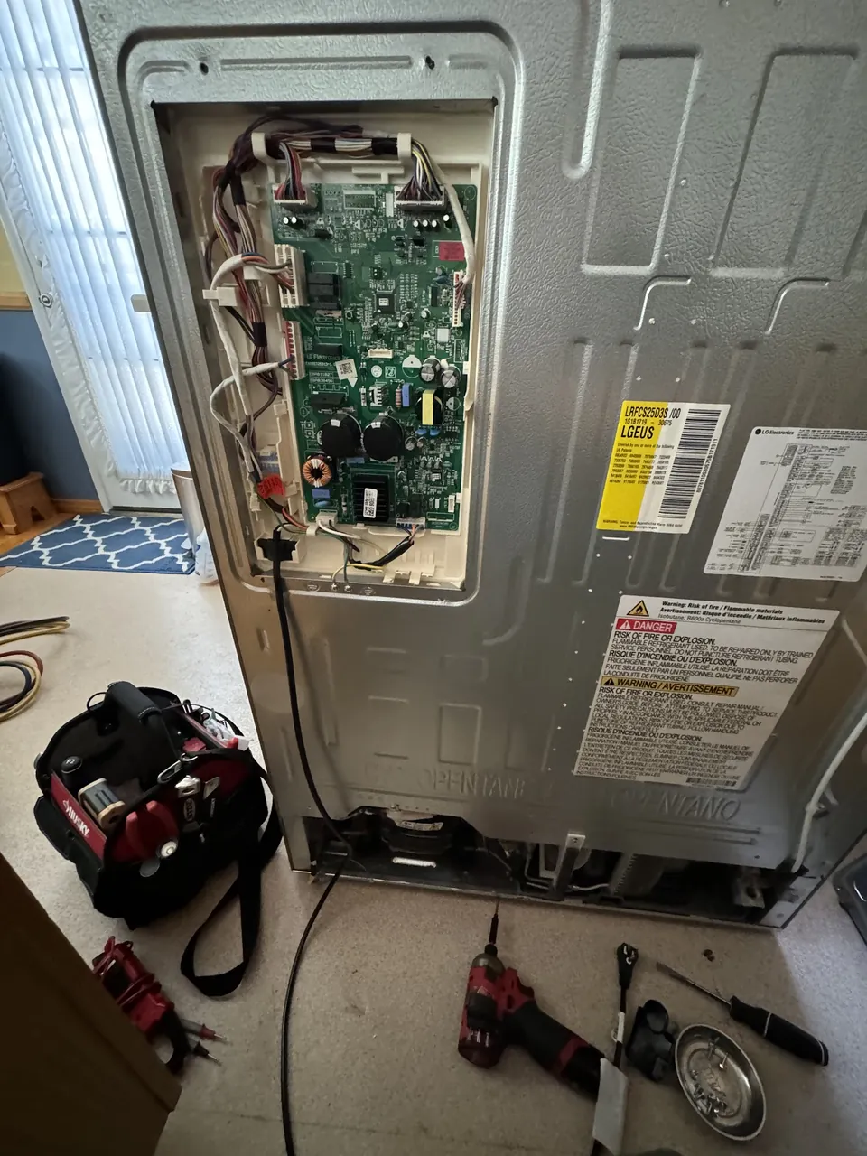 Refrigerator
                         pulled out from the wall with the back panel removed and the inverter
                         board exposed