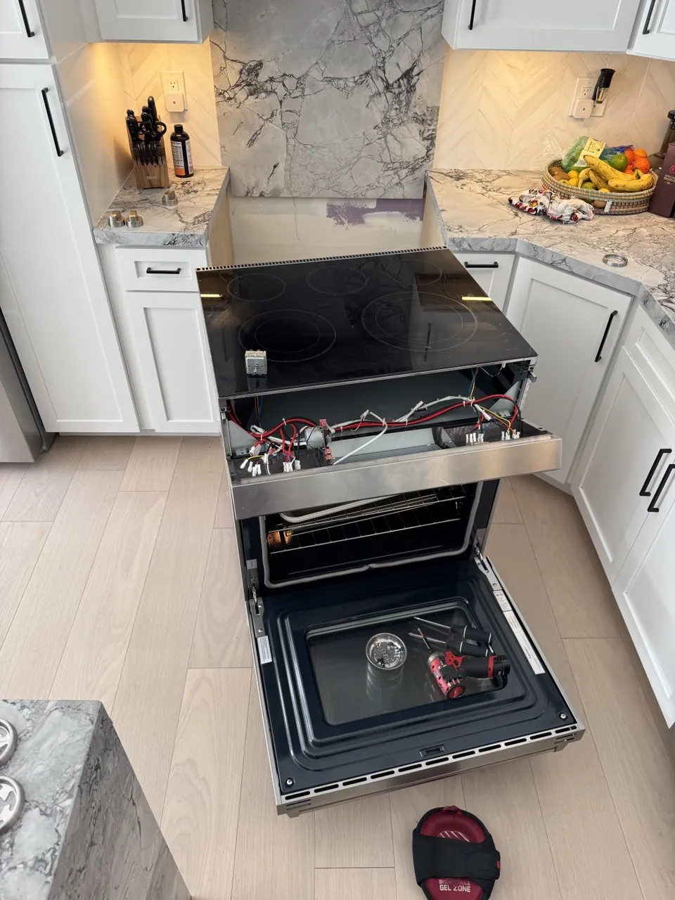 Slide-in range with the cooktop lifted and the oven door open