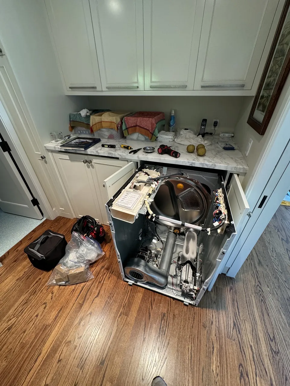 Dryer opened up out of the cabinet with the internals exposed