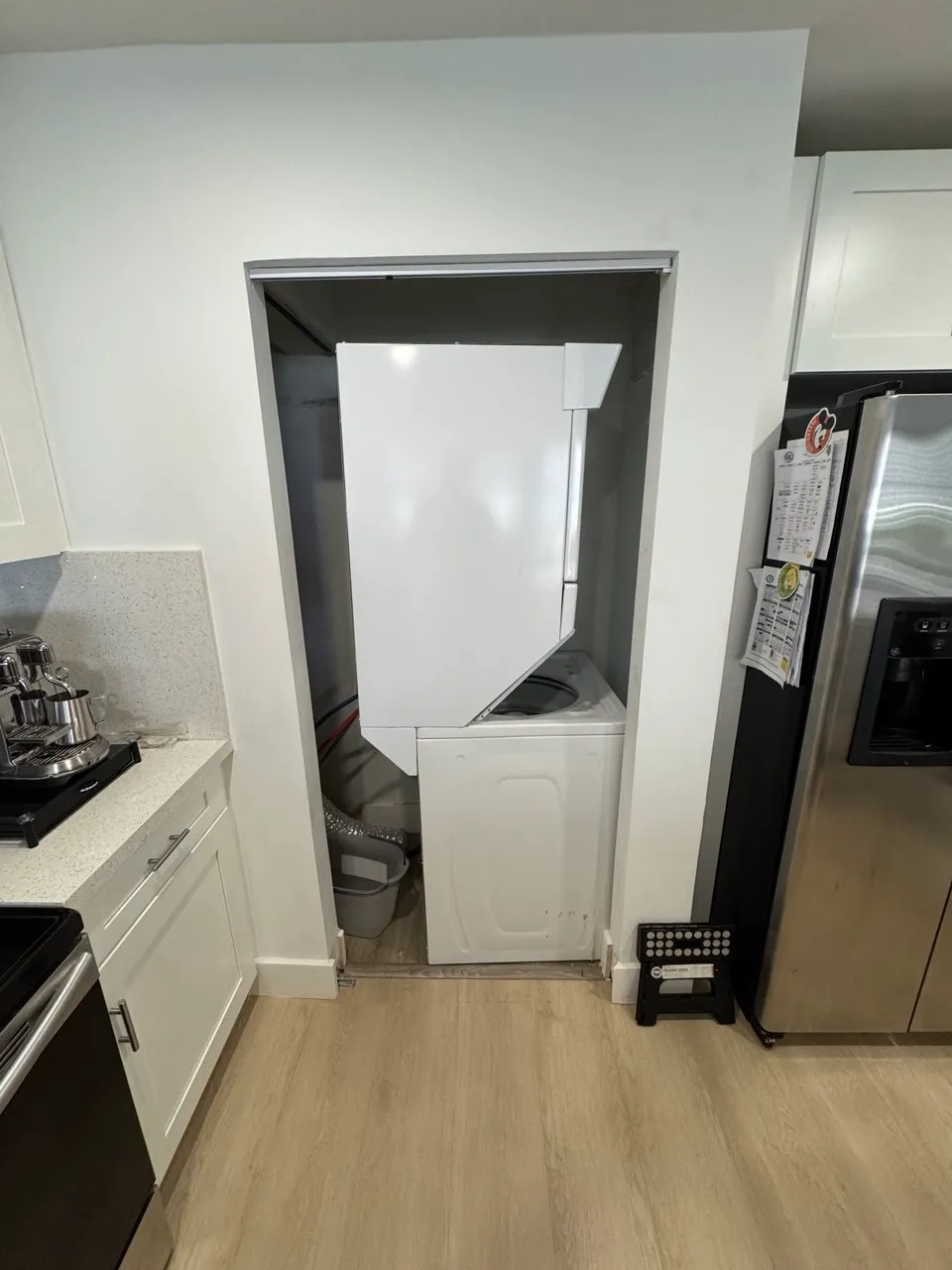 Stacked washer and dryer in a kitchen closet with the upper dryer door open