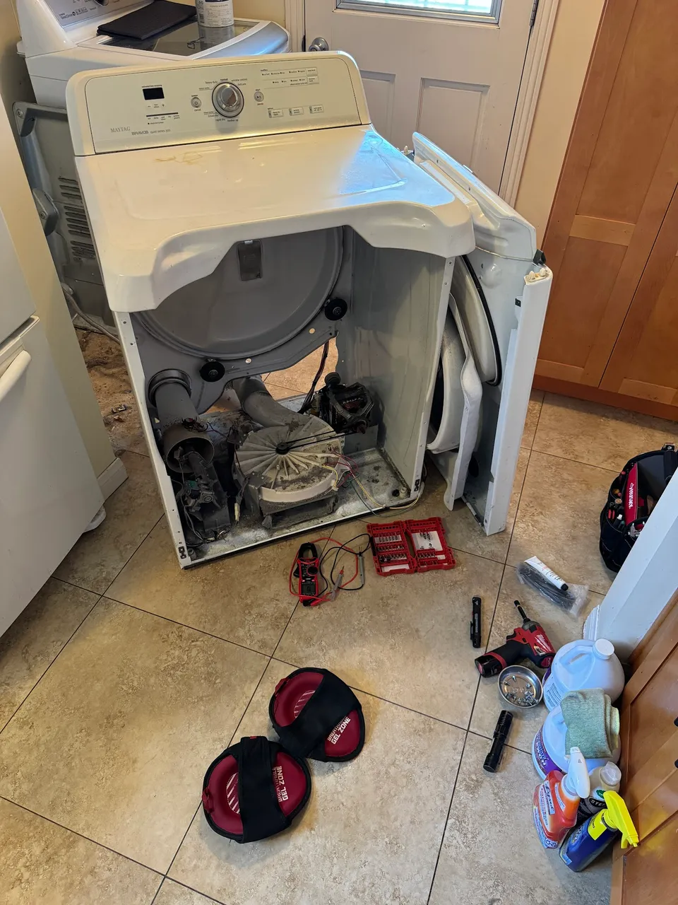 Dryer pulled out and opened in a kitchen with components arranged on the floor
