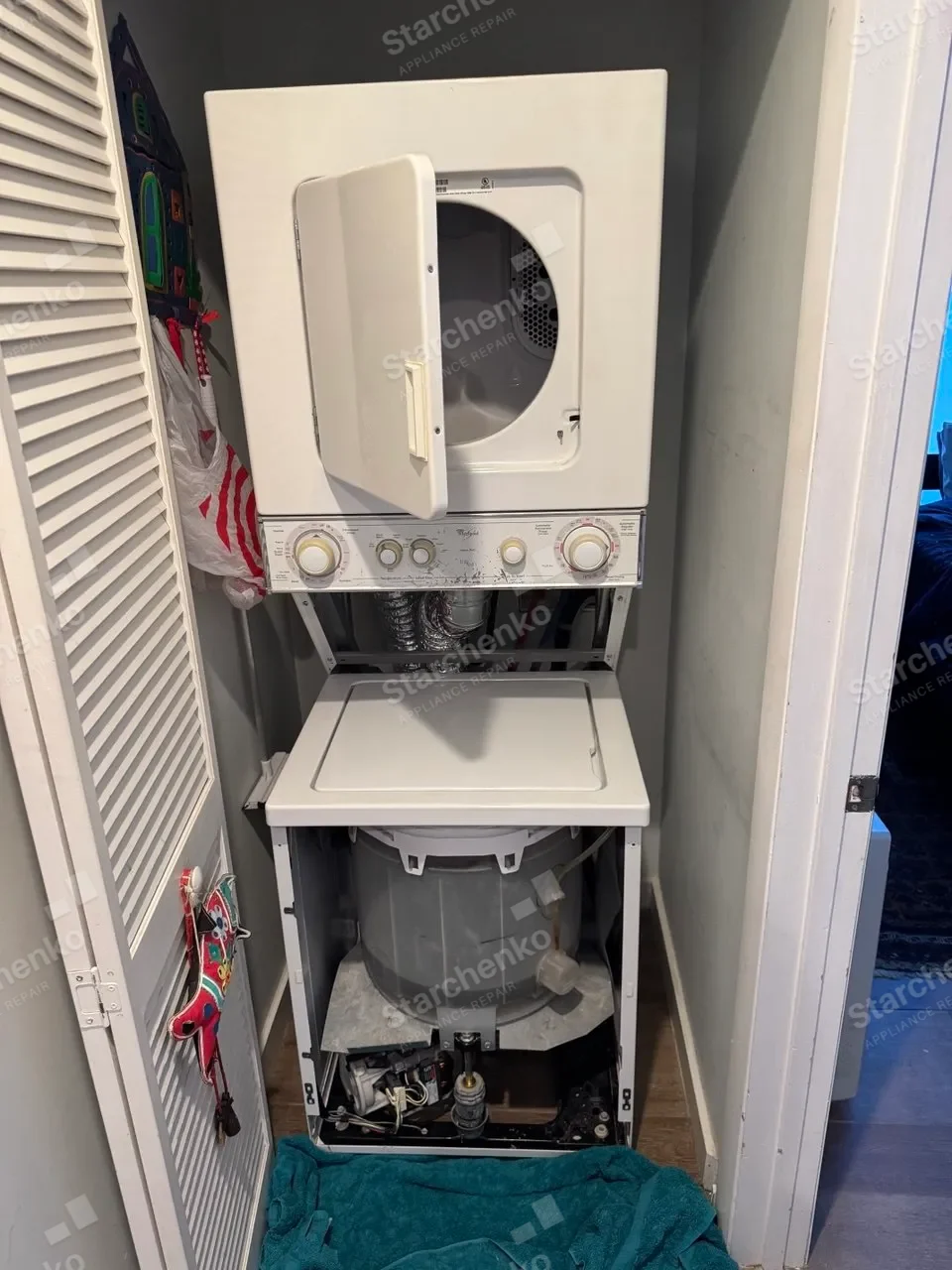 Stacked Whirlpool laundry center opened with the washer tub and lower components exposed