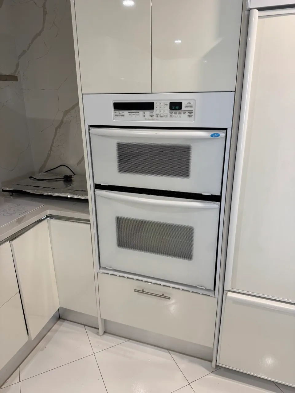 White double wall oven built into a kitchen column next to a refrigerator