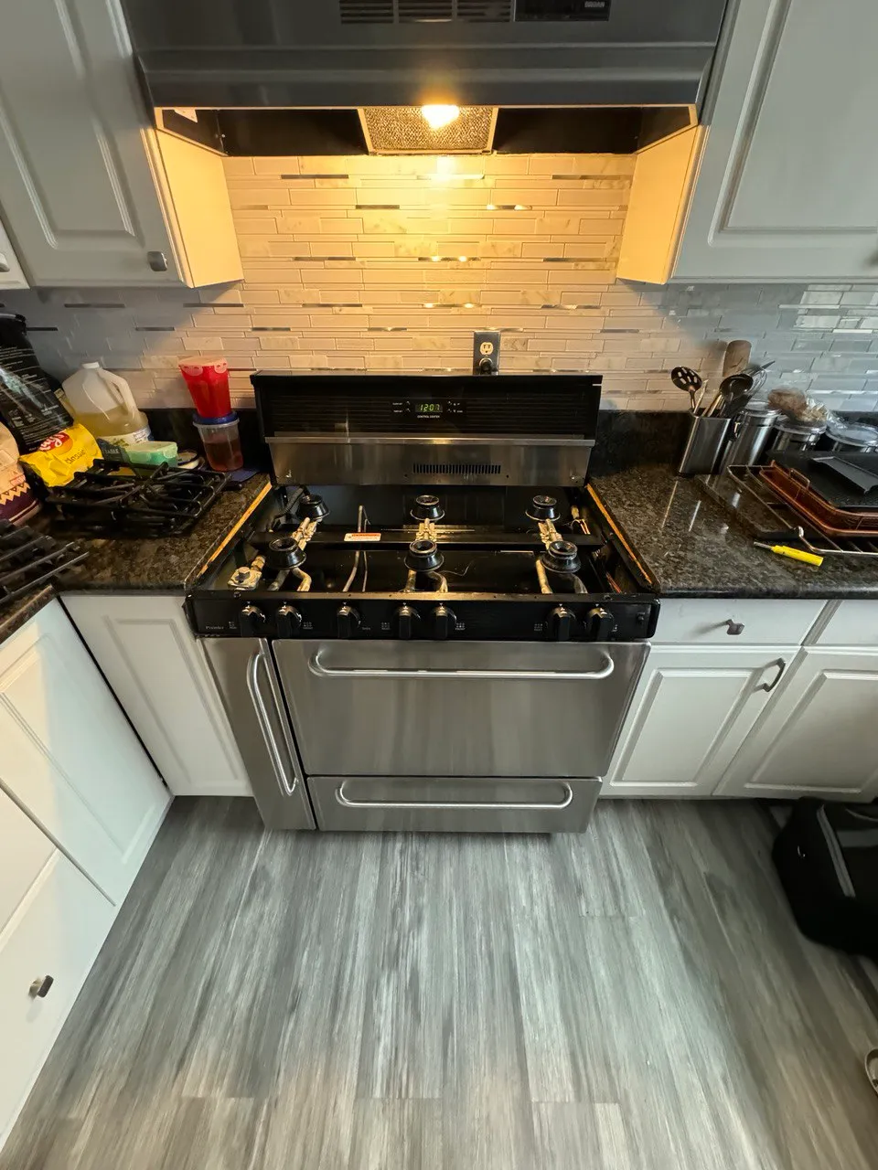 Stainless gas range between kitchen cabinets