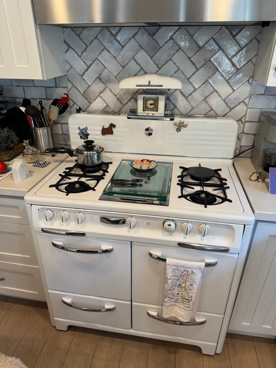 Vintage white gas stove with the oven and broiler doors closed in a tiled kitchen