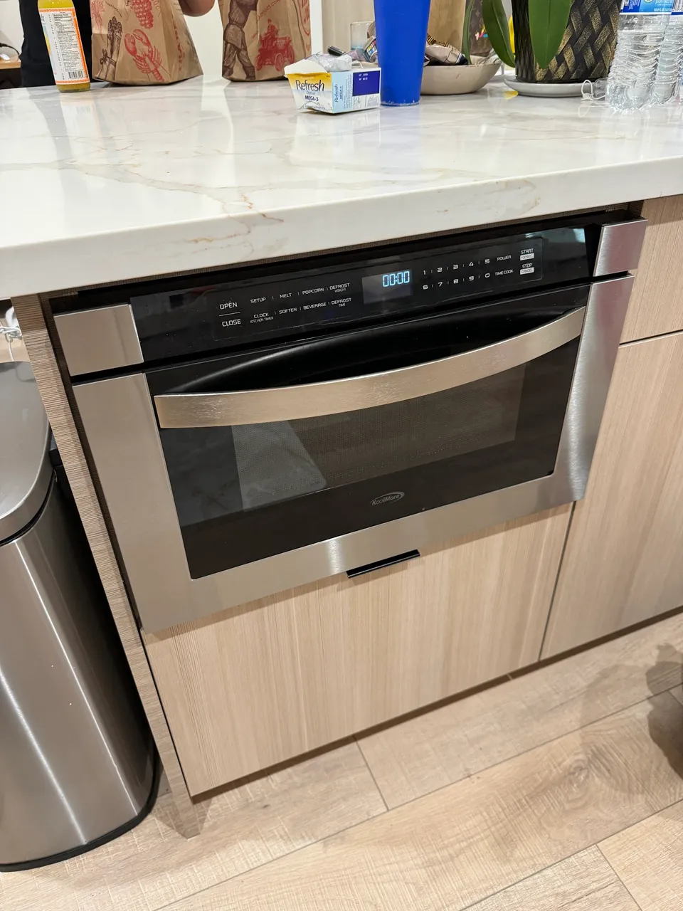 Stainless microwave drawer built into a kitchen island below the countertop