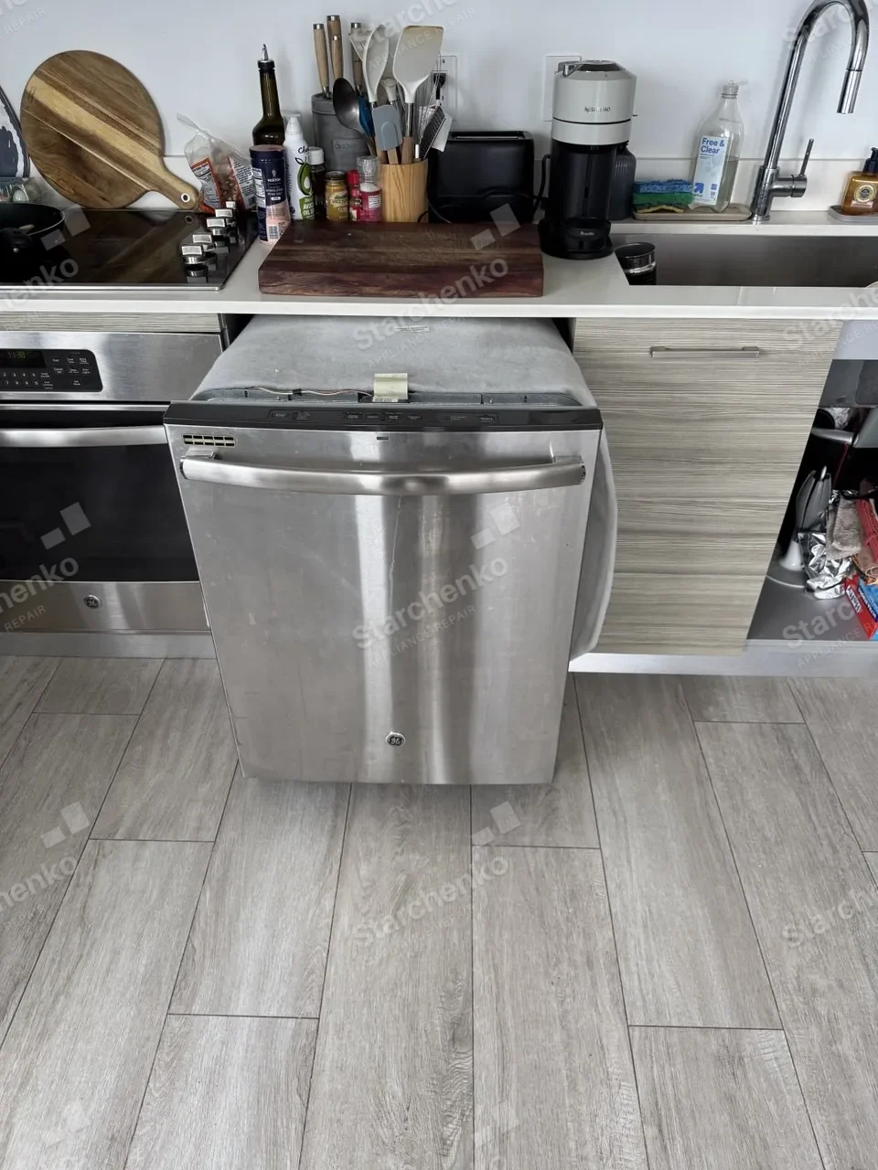 Stainless GE dishwasher pulled out from under the counter onto the kitchen floor