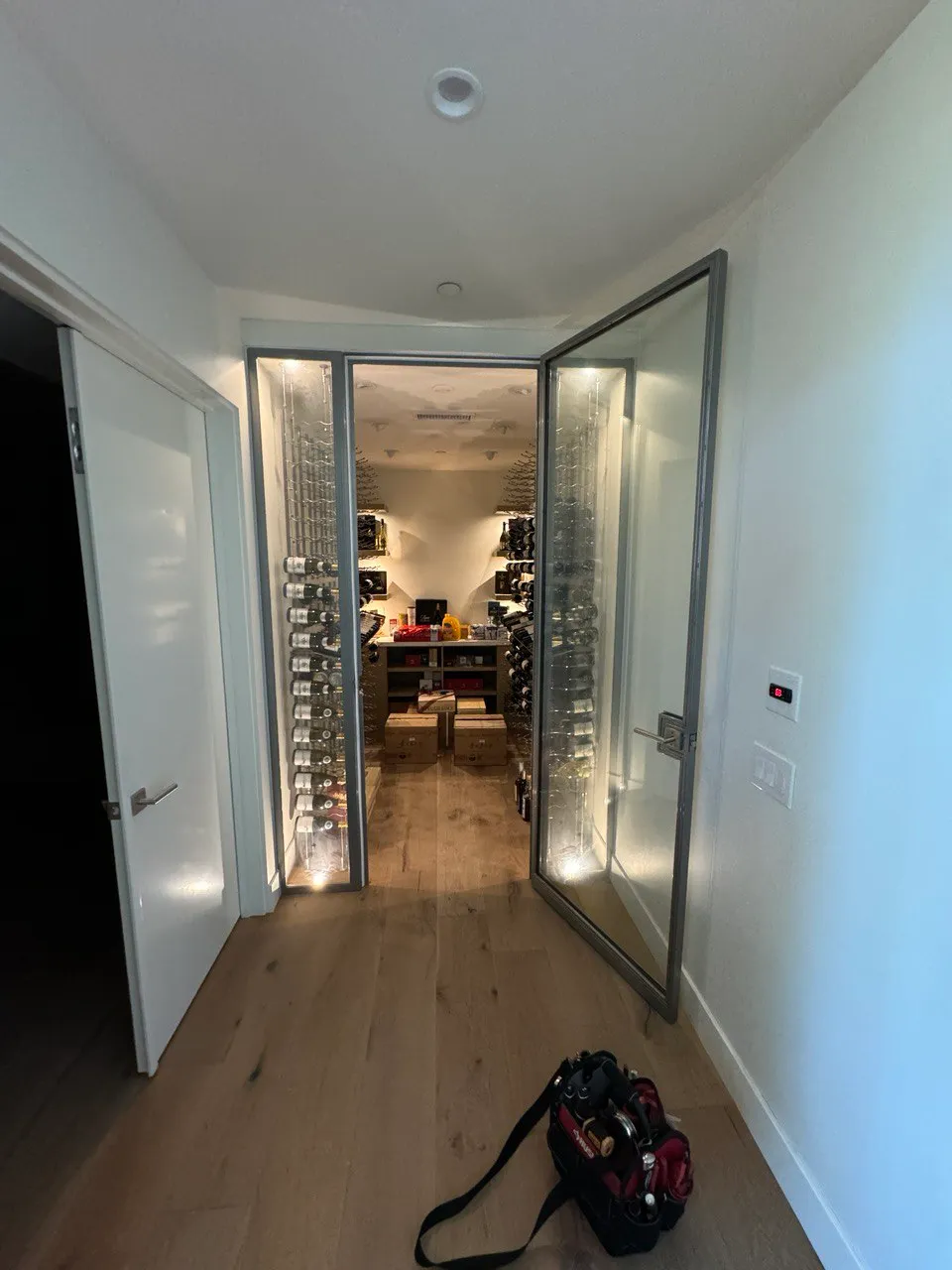 Walk-in wine cellar with its glass door open for cooling-unit service