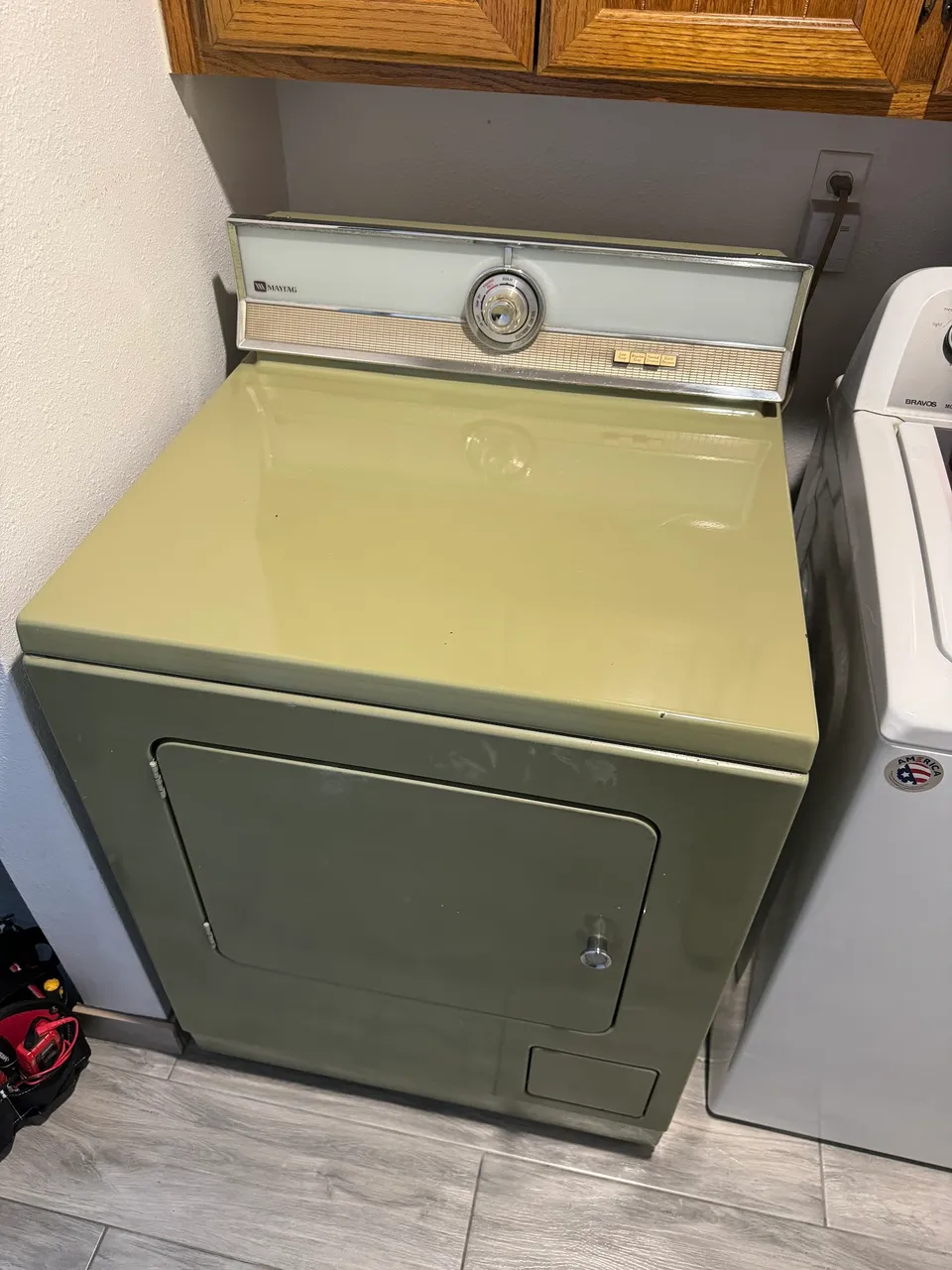 Older dryer standing next to a washer in a laundry room