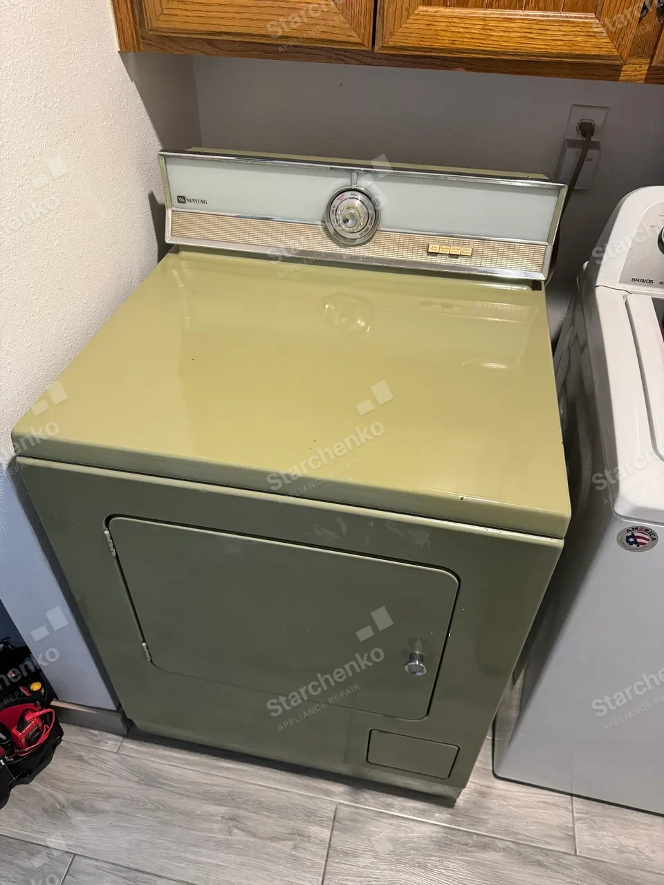 Older Maytag dryer standing next to a washer in a laundry room