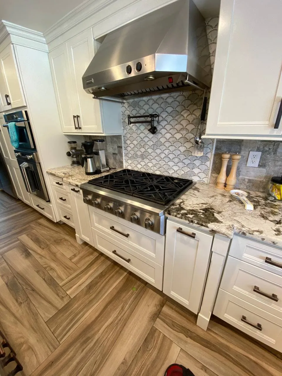 Pro-style gas rangetop in a white kitchen with a stainless hood above