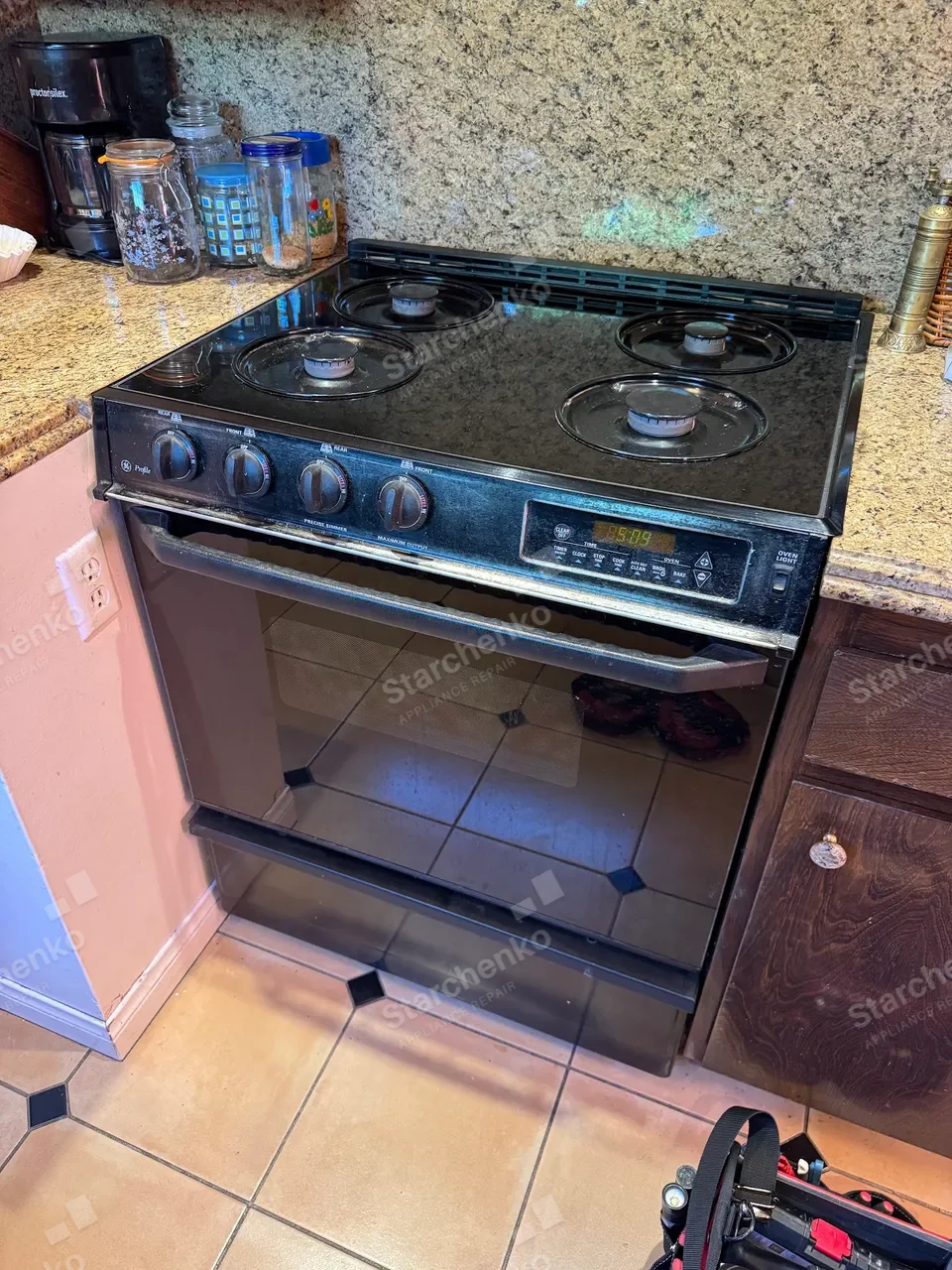 Black GE Profile gas range installed between kitchen cabinets
