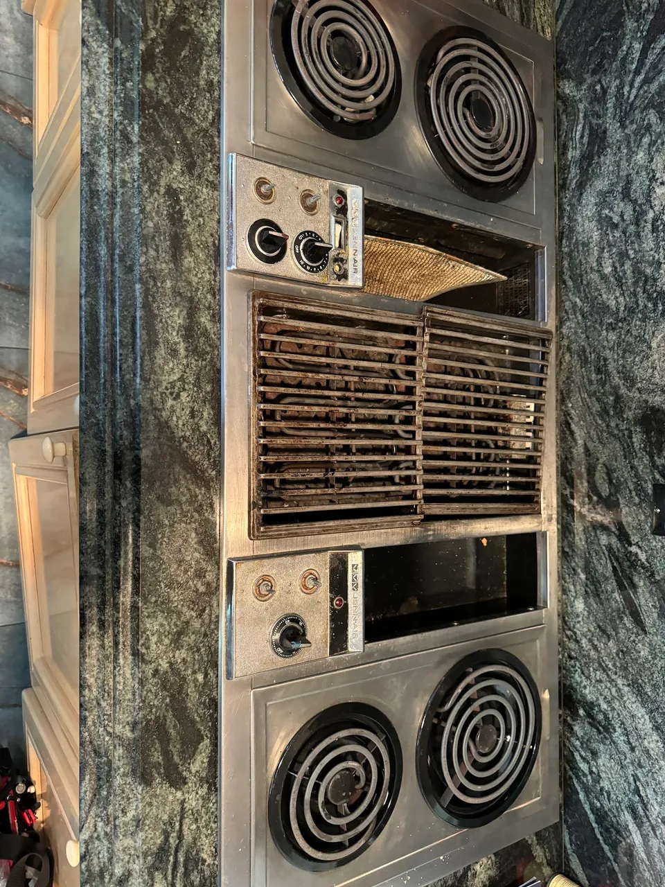 Older electric cooktop with an integrated grill set into a marble countertop