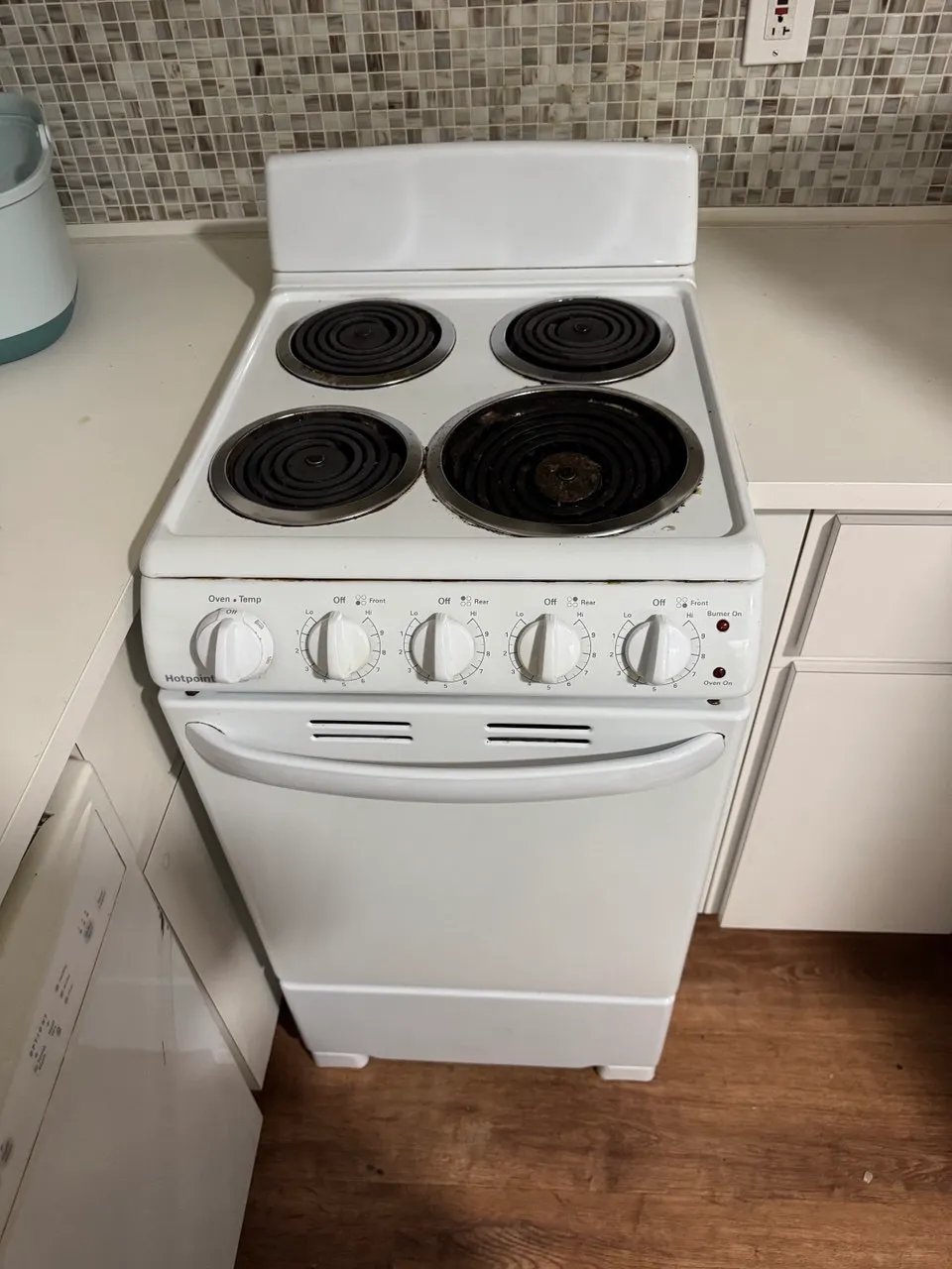 White electric coil range with four burners in a small kitchen