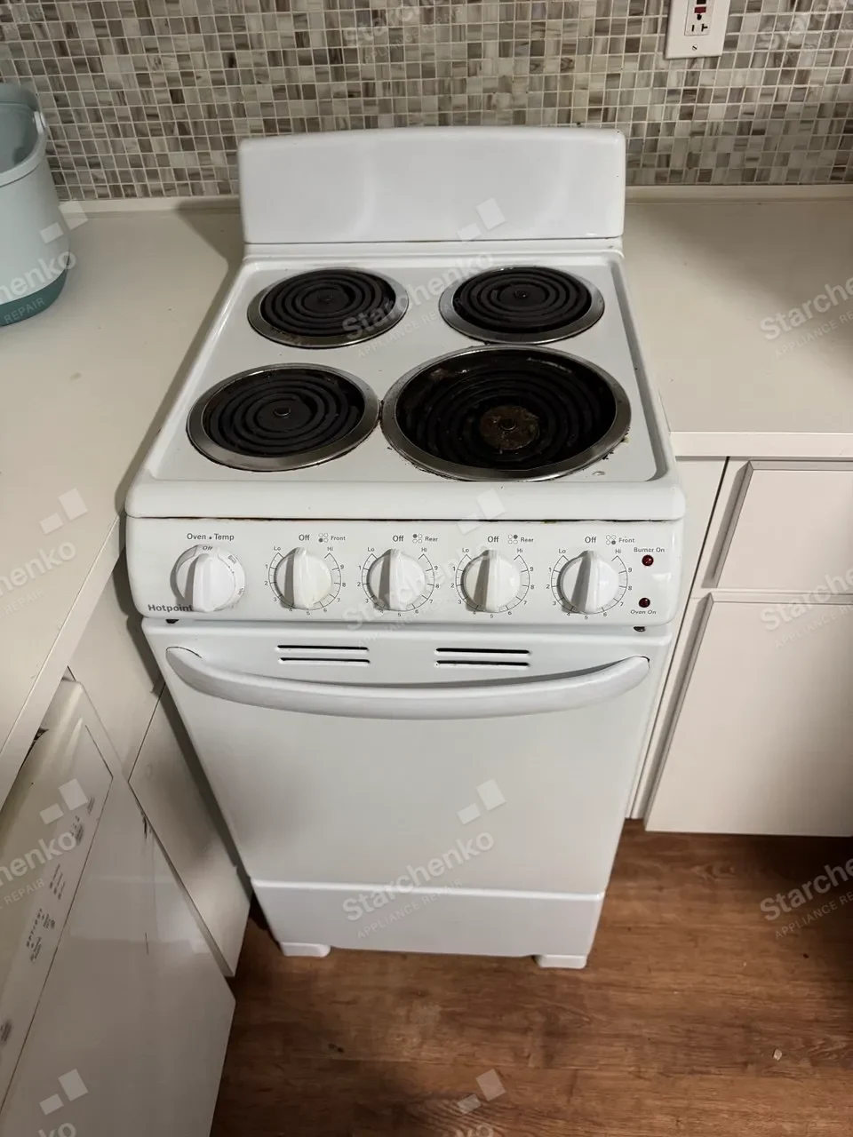 White Hotpoint electric coil range with four burners in a small kitchen