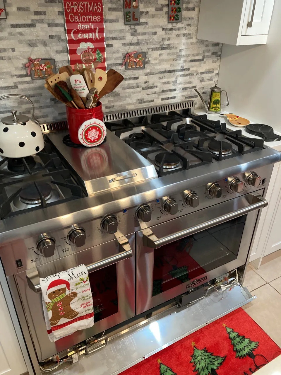 Pro-style gas range with the lower access panel dropped open in a decorated kitchen