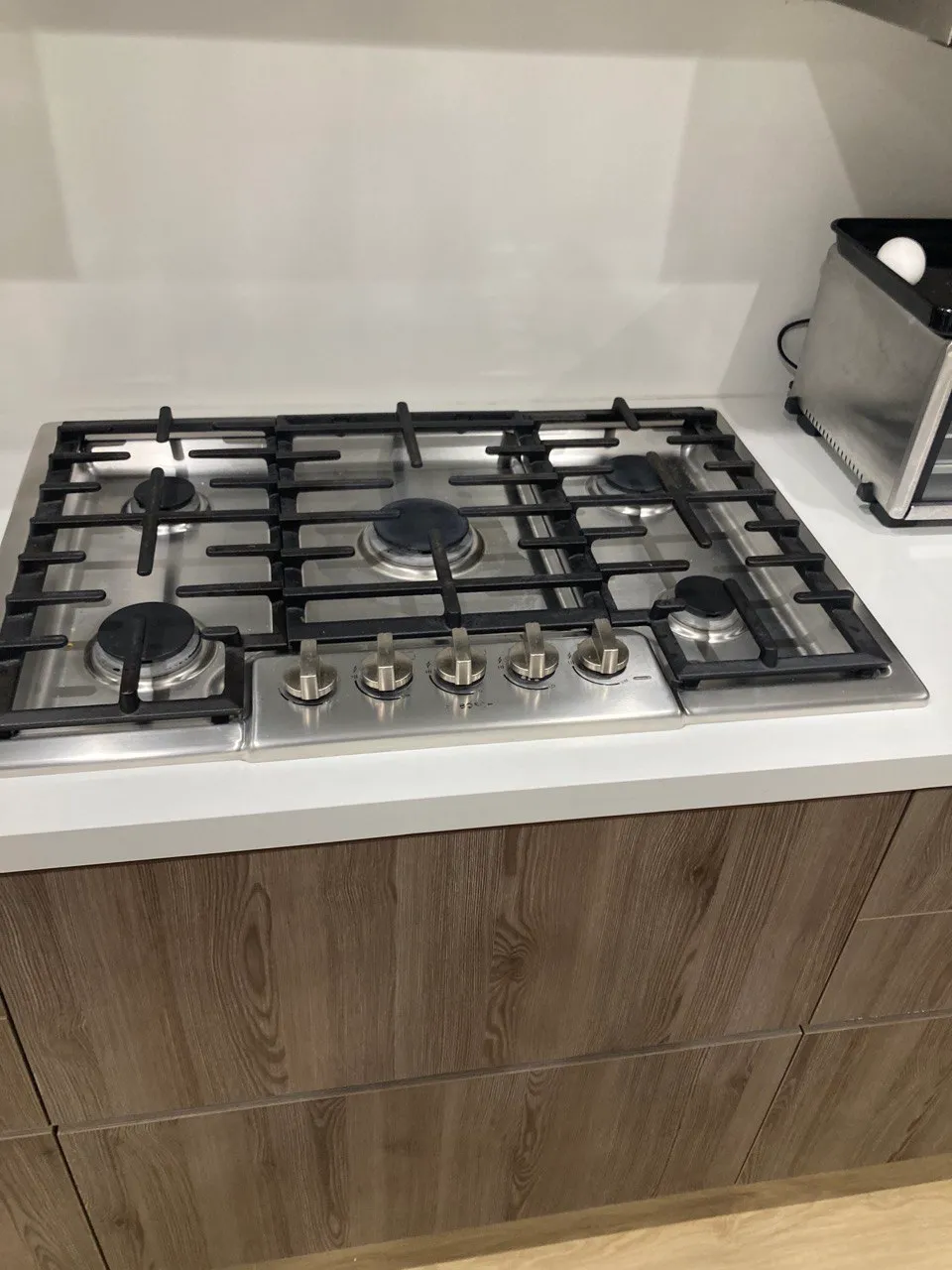 Five-burner gas cooktop set into a white countertop