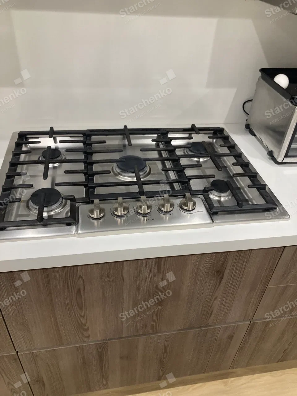 Five-burner Bosch gas cooktop set into a white countertop