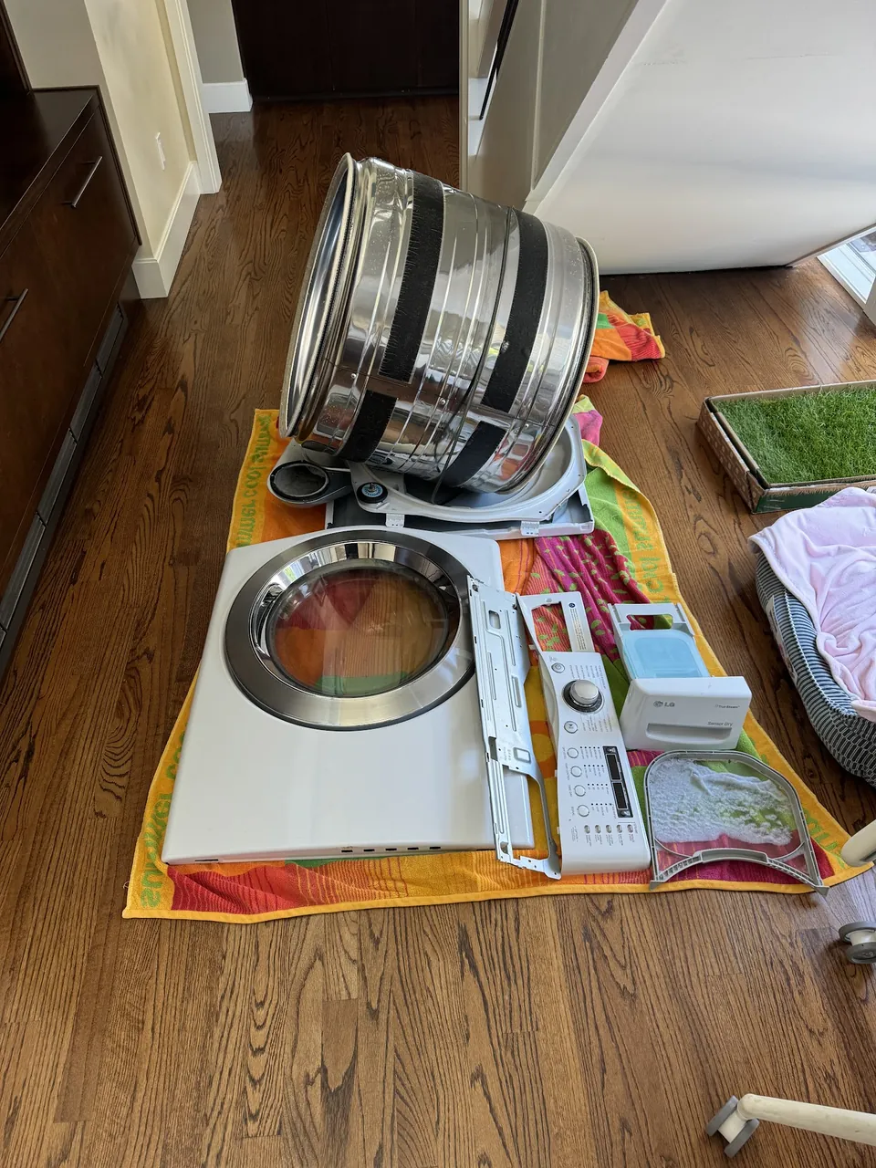 Dryer taken apart on the floor: the drum out of the cabinet with the
                         front panel beside it