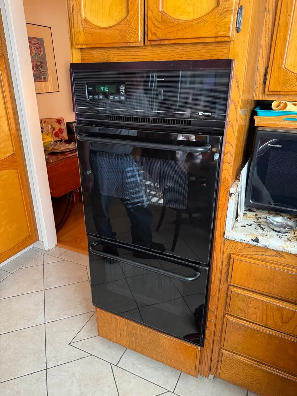 Black built-in wall oven in oak cabinets with a microwave beside it