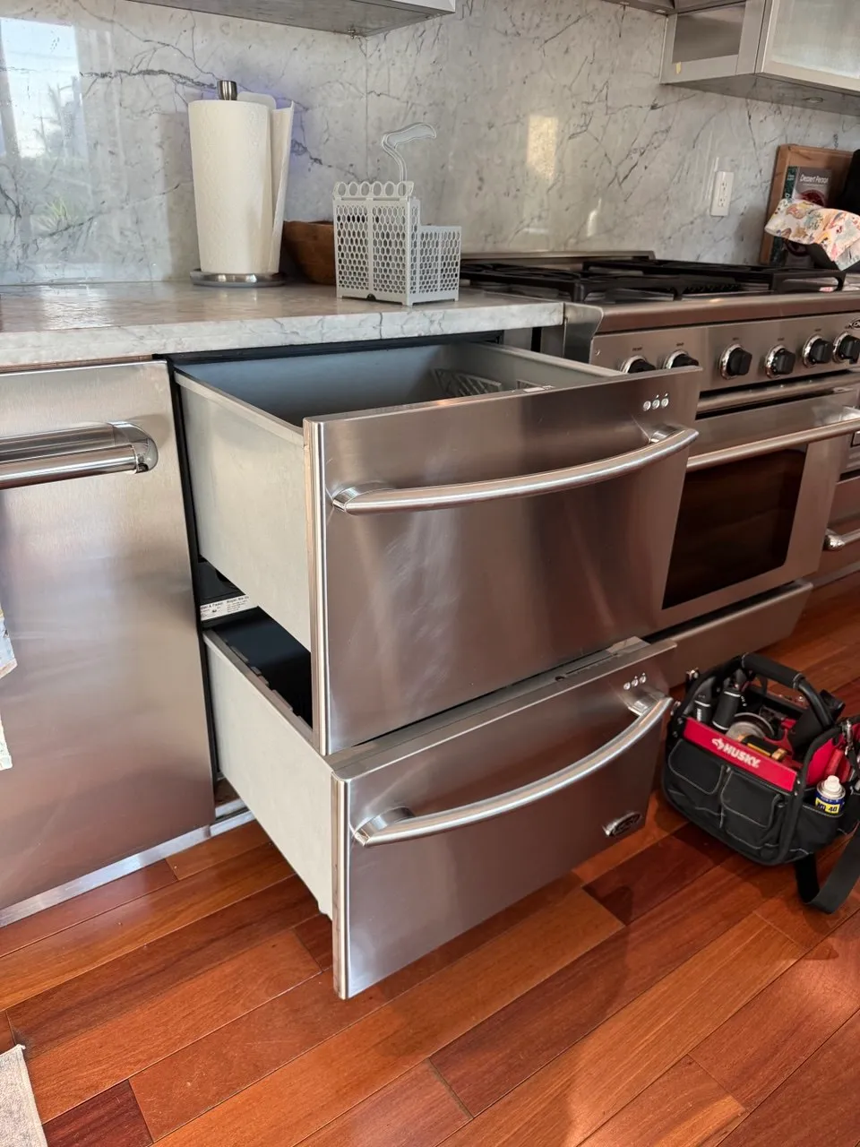 Two stainless dishwasher drawers pulled open below a counter