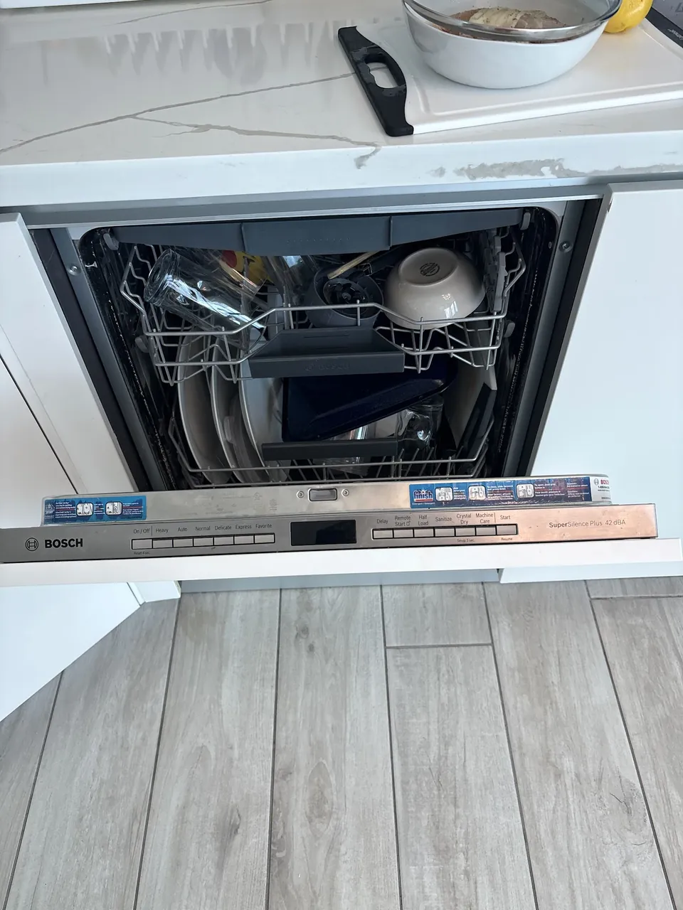 Built-in Bosch dishwasher with the door open and a rack rail removed