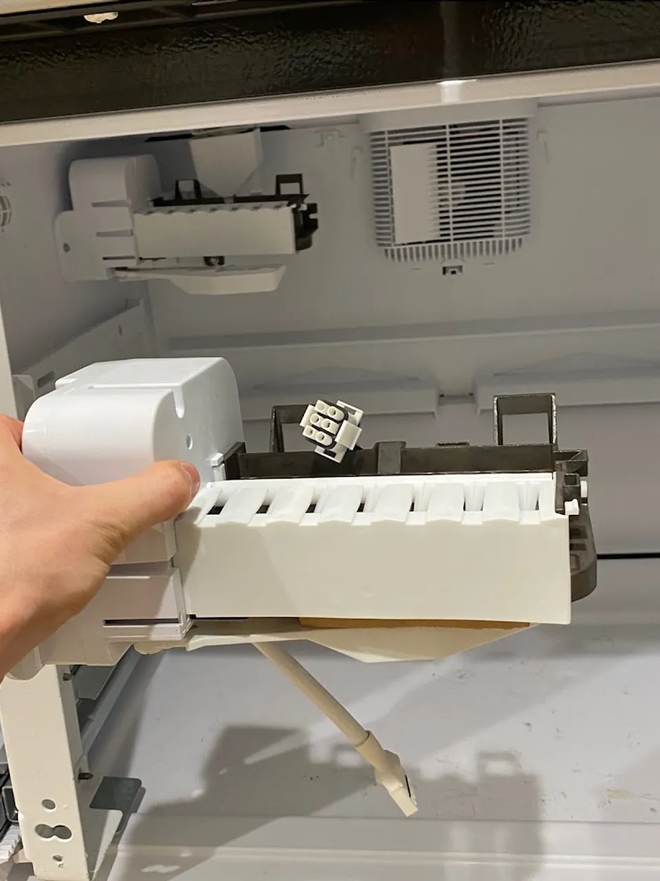 Hand pulling the ice maker tray module out of the freezer drawer
