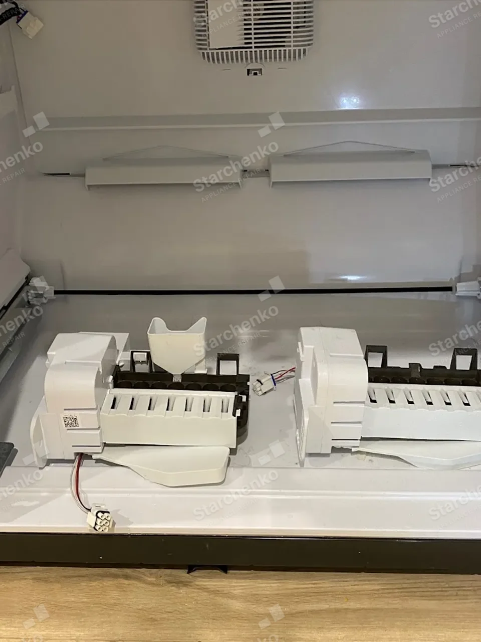 GE Monogram ice maker assembly and wiring exposed inside the open freezer drawer