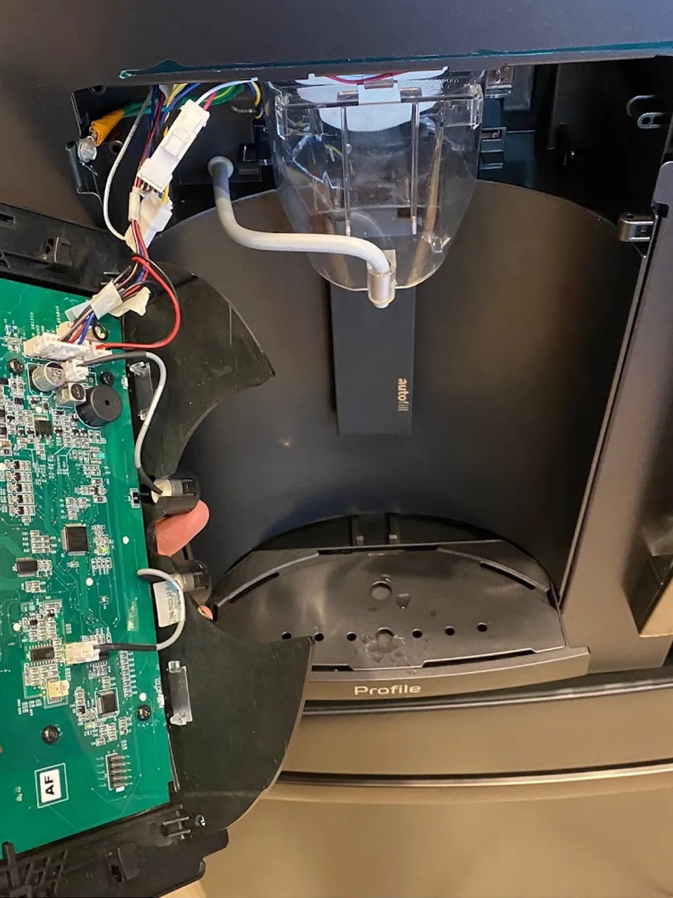 Refrigerator dispenser panel opened with the ice maker control board in hand