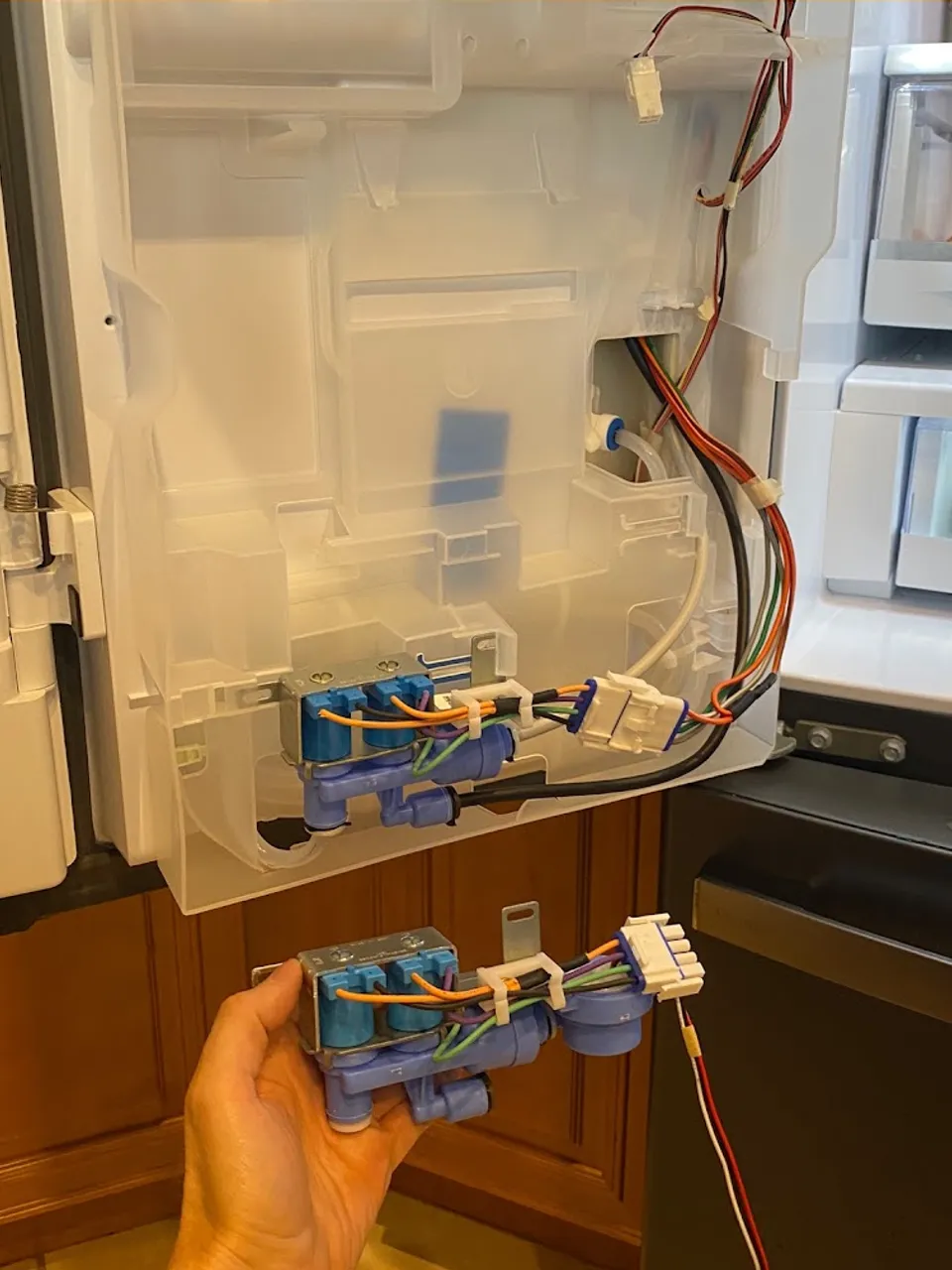 Water inlet valves for the ice maker behind the opened refrigerator panel
