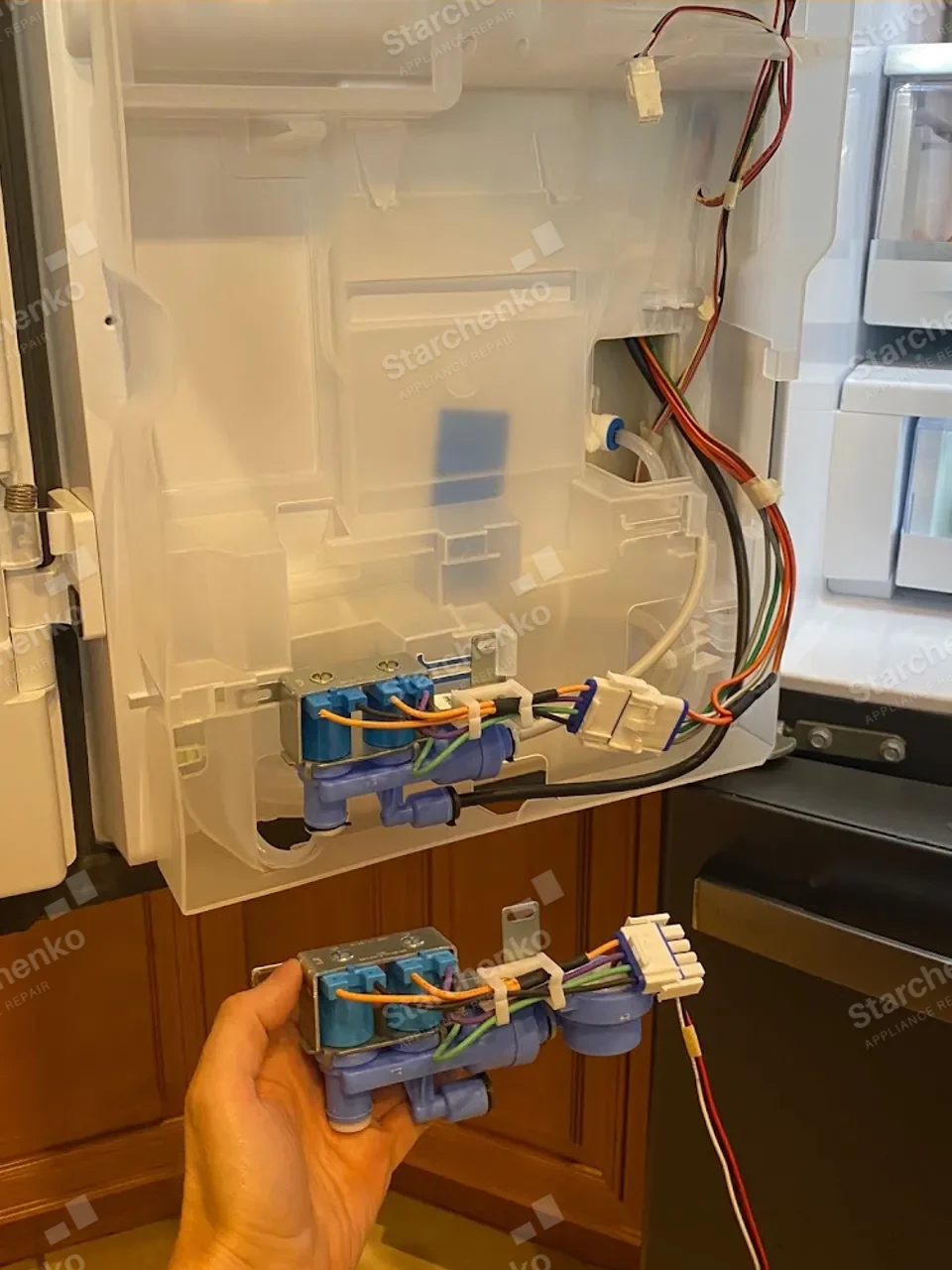Water inlet valves for the GE Profile ice maker behind the opened refrigerator panel