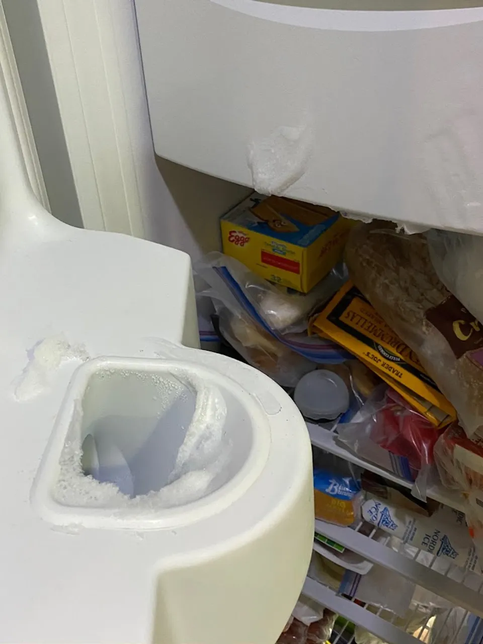 Freezer ice maker chute frozen over with a block of ice