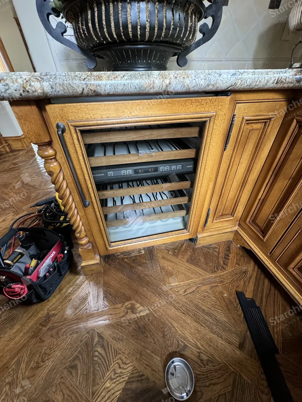 Sub-Zero built-in wine cooler with its door open in a wood-panel kitchen, the display reading 81 degrees