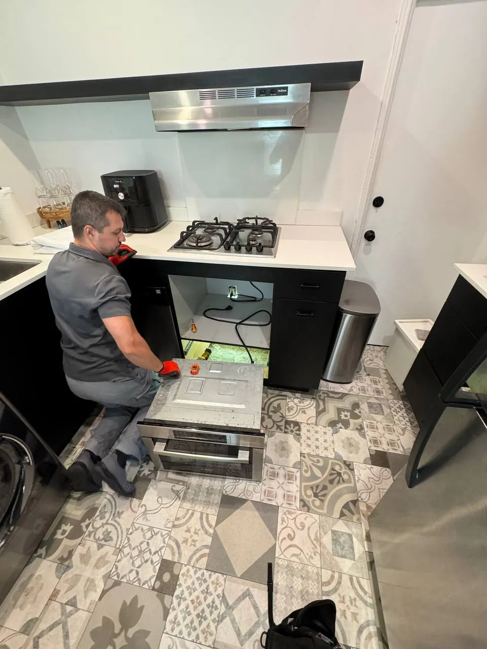 Technician working on a built-in oven under the countertop
