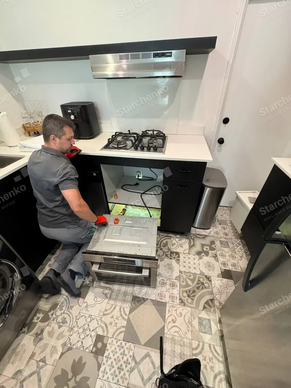 Technician working on a Bosch built-in oven under the countertop