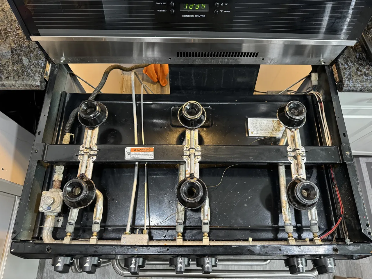 Gas range with the cooktop lifted and burner assemblies exposed