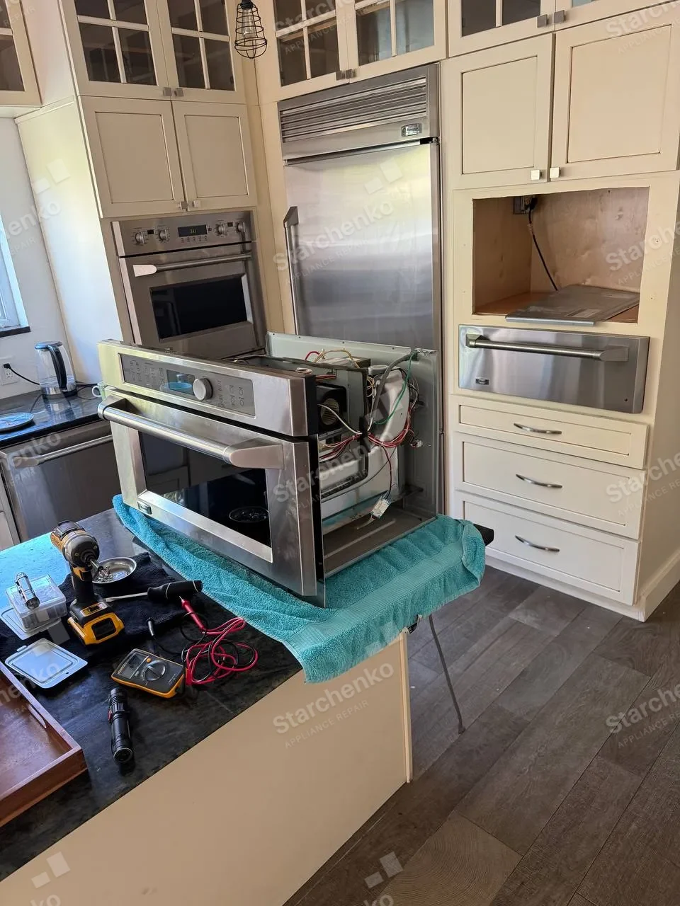 GE Monogram built-in microwave pulled out of the cabinet onto a work stand