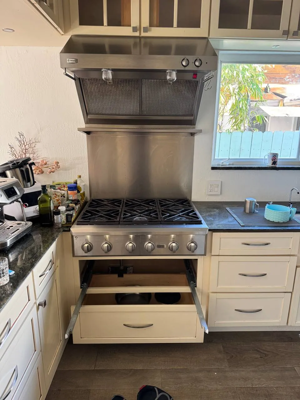 Pro-style gas range under a stainless hood with the drawer pulled open