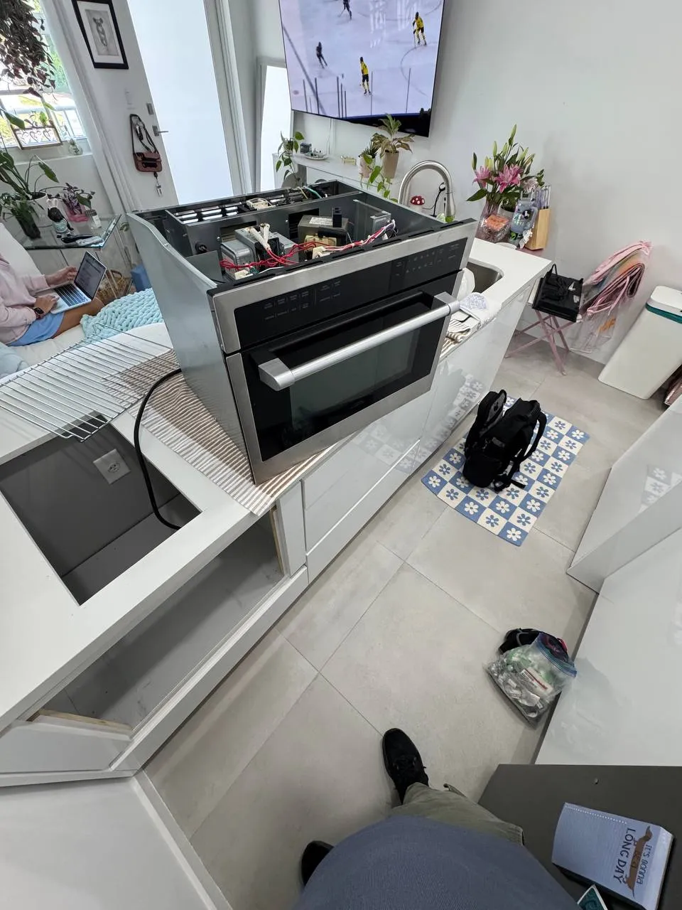 Built-in microwave slid out of the cabinet with the top cover off and the transformer exposed