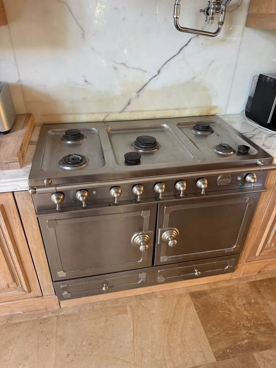 Brass-trimmed pro-style gas range standing in a stone kitchen