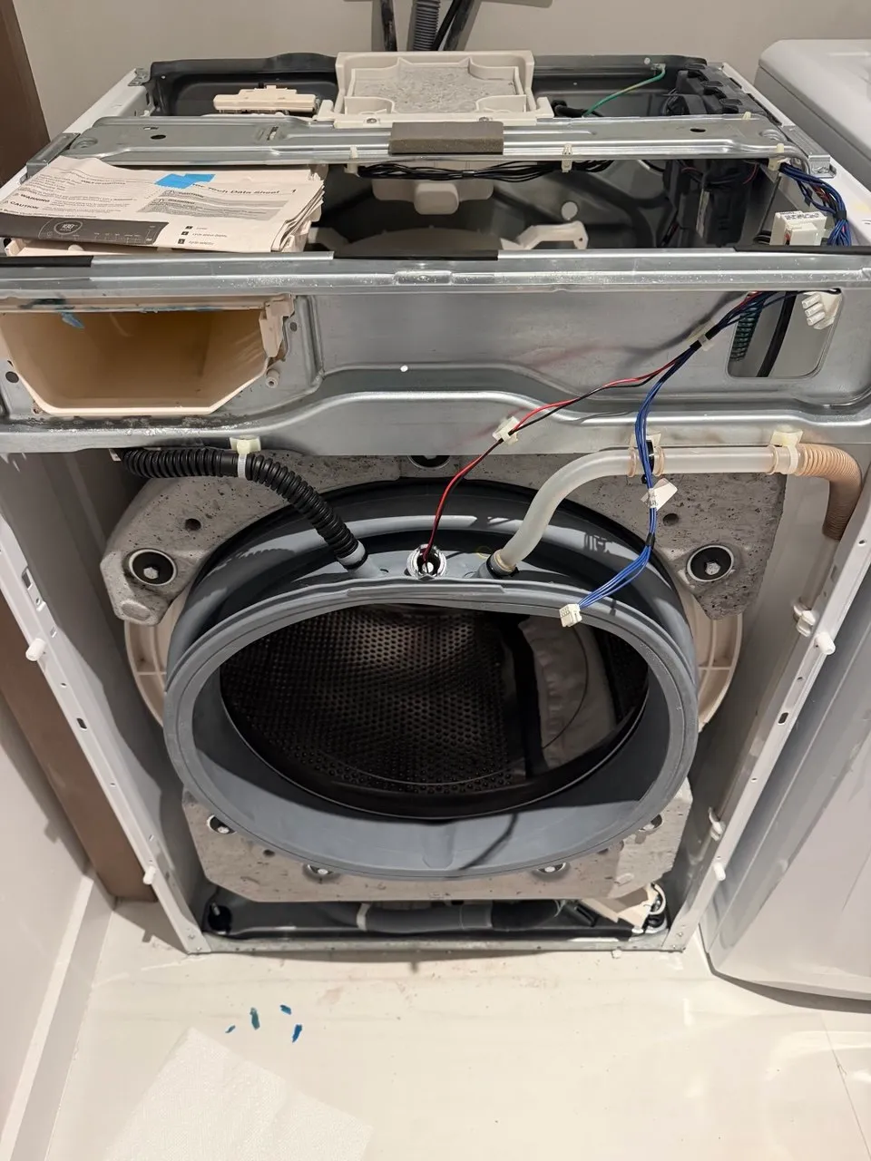 Washer opened up with the outer tub, water hoses and drum exposed