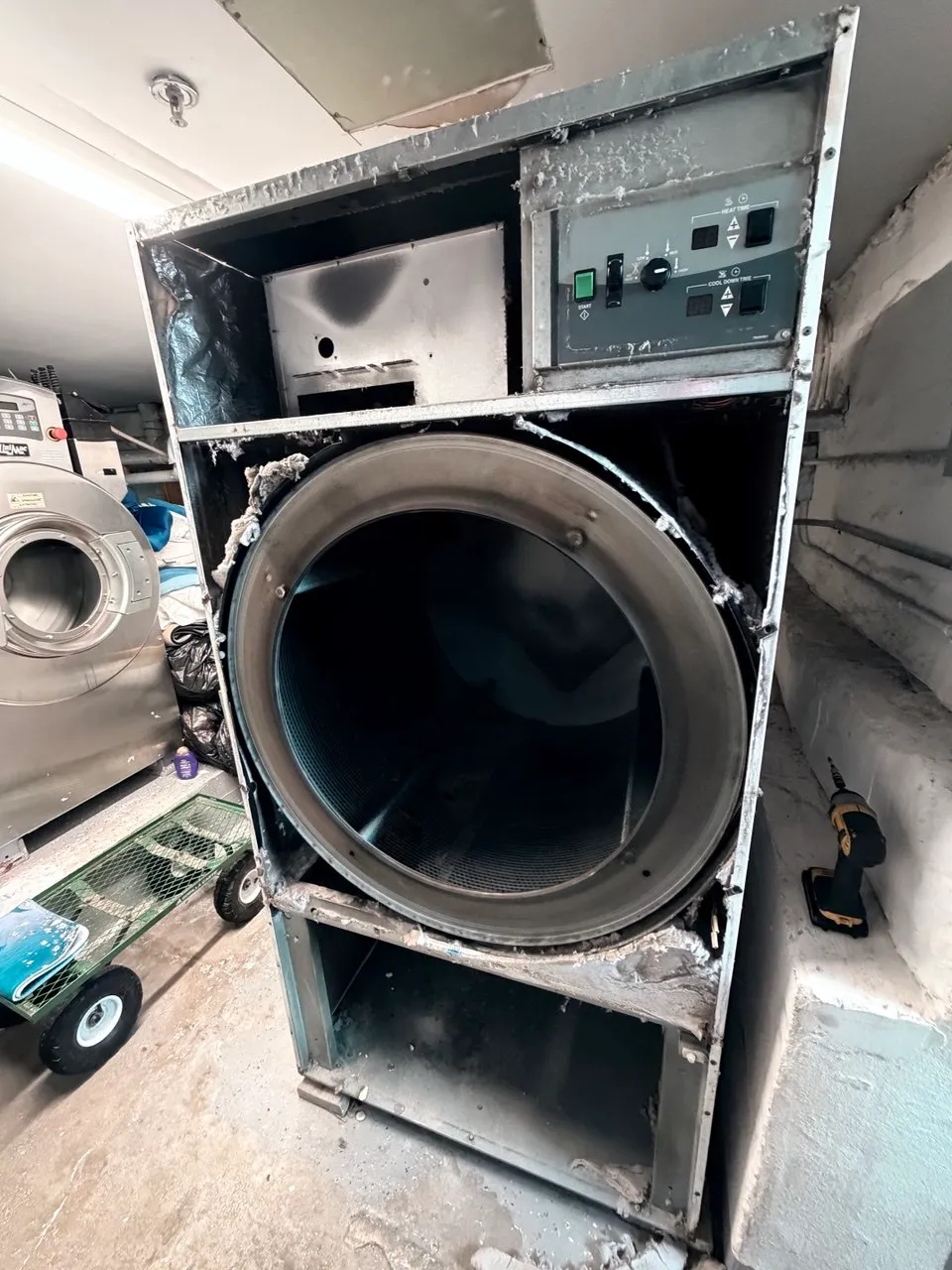Commercial dryer opened with its drum, lint filter housing, blower and vent path exposed