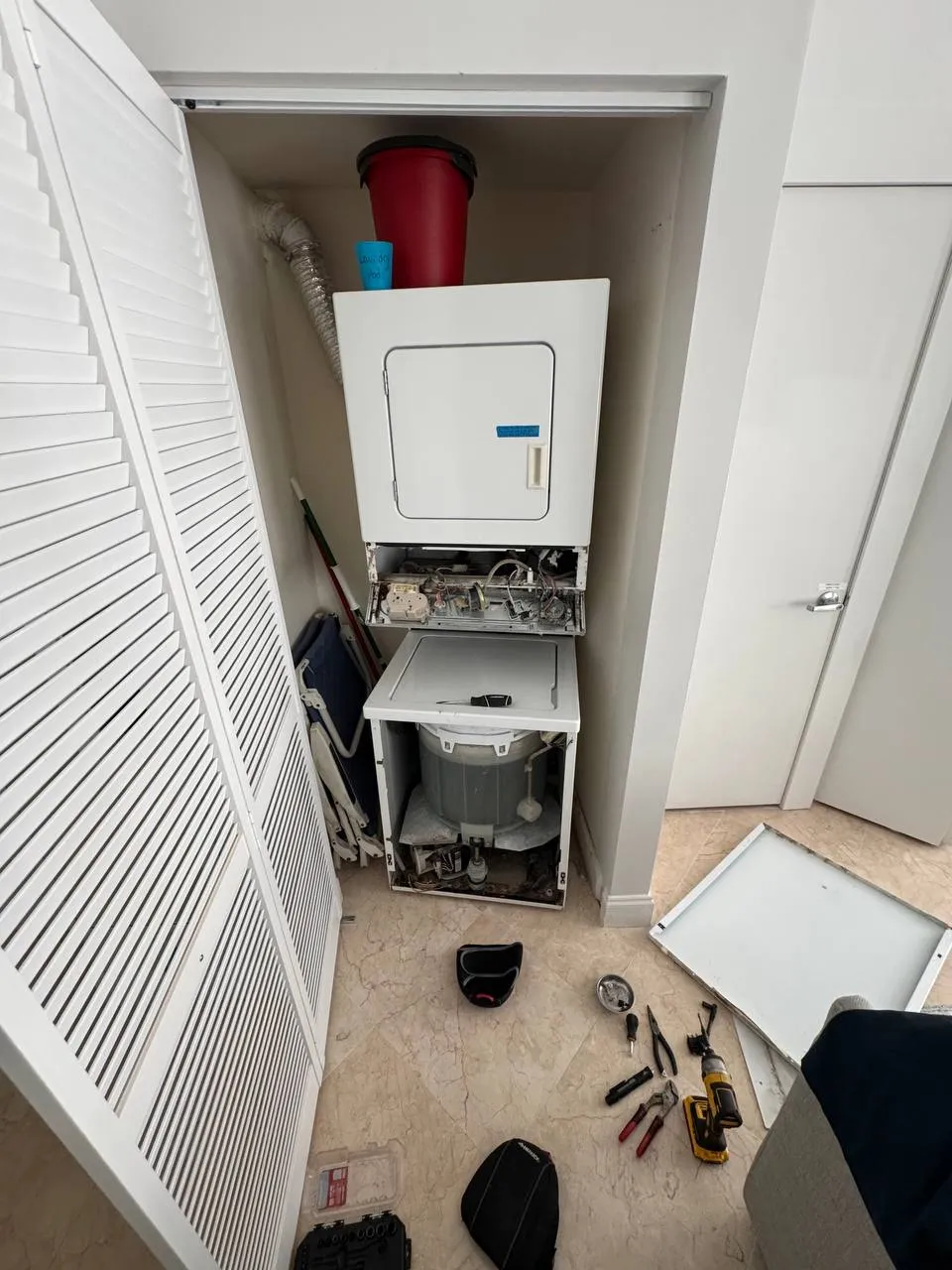Stacked laundry center opened with the dryer controls and washer tub exposed