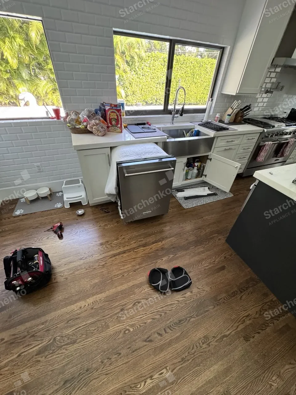 KitchenAid dishwasher pulled out from under the counter in a bright kitchen