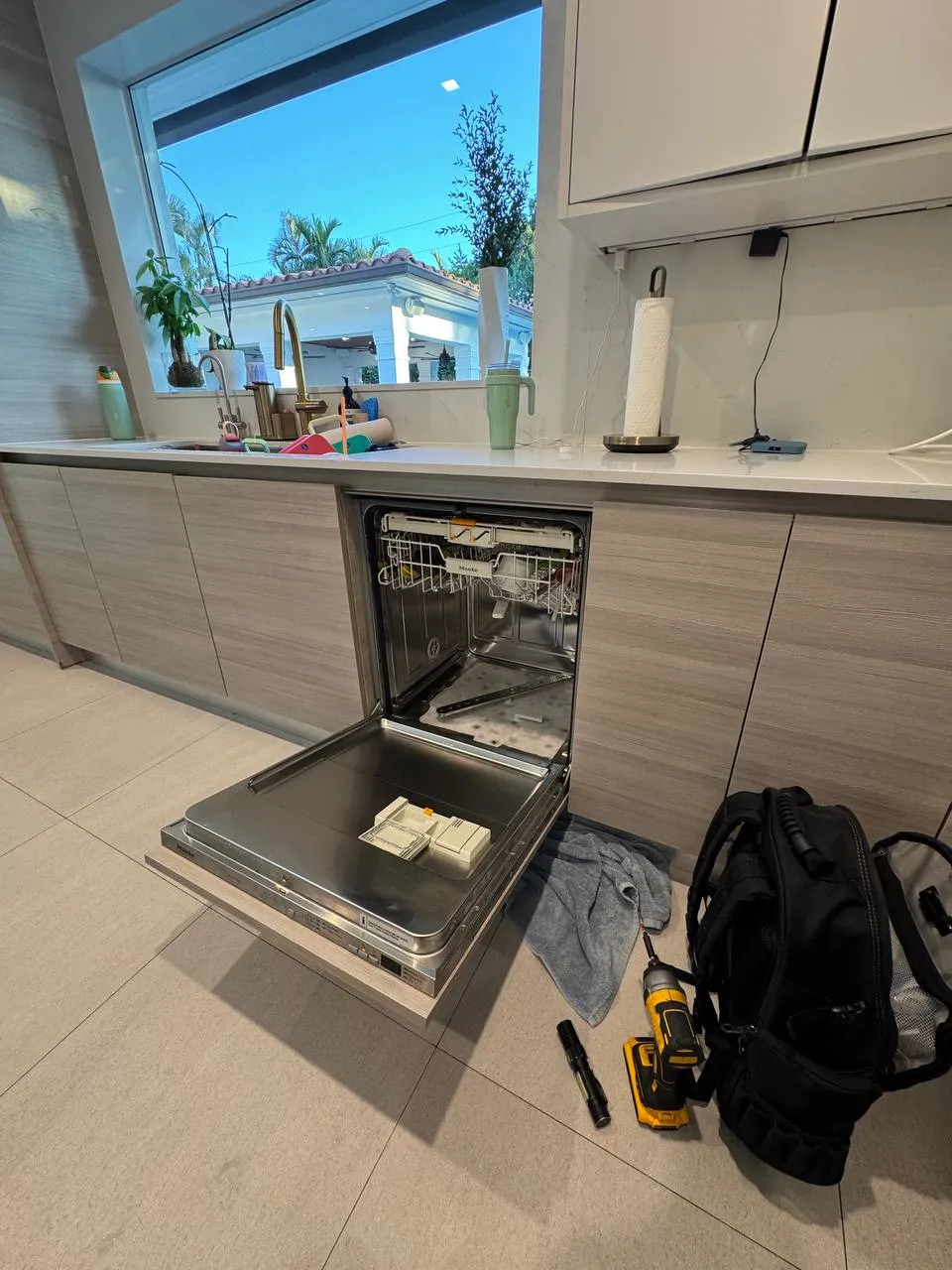 Built-in Miele dishwasher open with the detergent dispenser removed and resting on the door