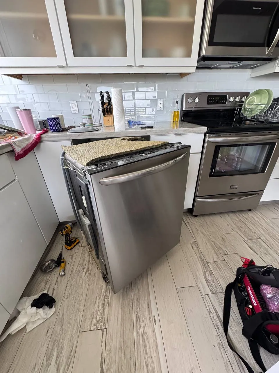 Stainless Frigidaire dishwasher pulled out from under the counter with the door swung open