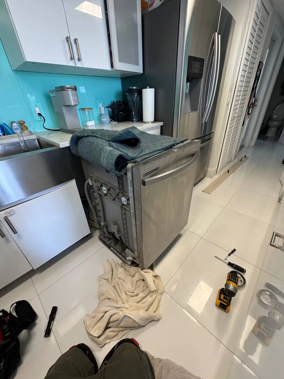 Stainless dishwasher pulled out with its side frame, wiring and hoses exposed