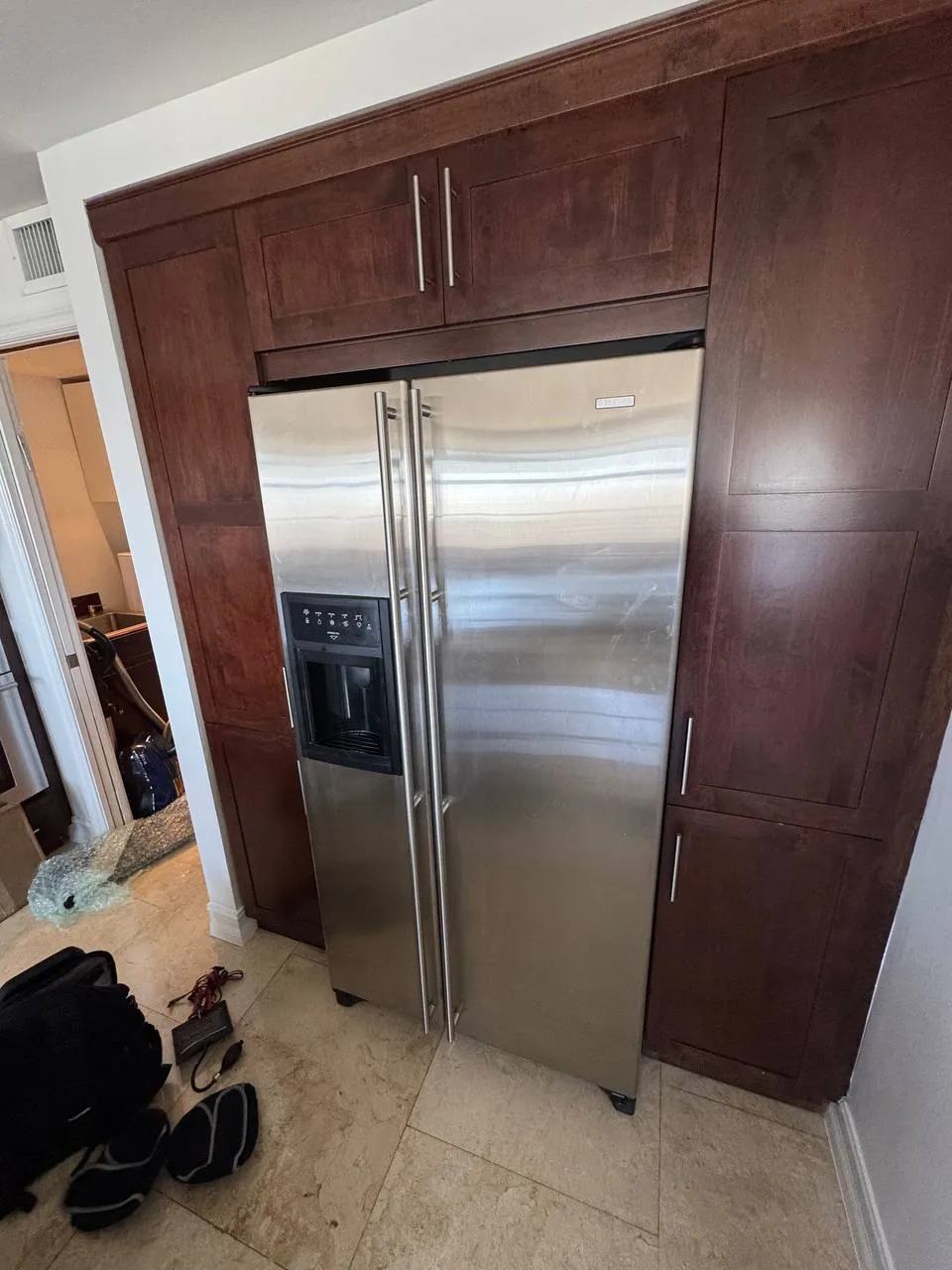 Built-in stainless side-by-side freezer and refrigerator set into dark wood cabinetry