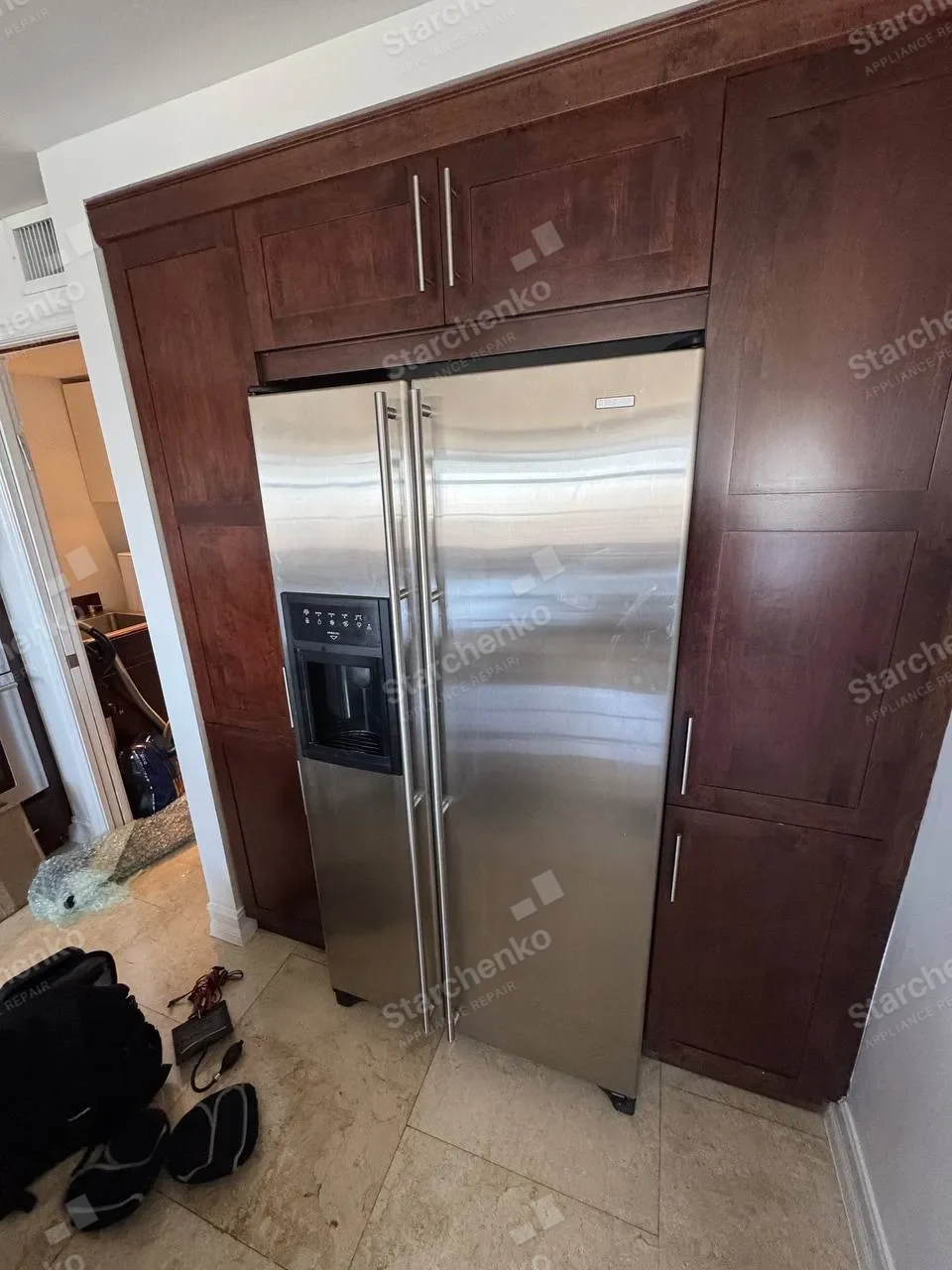 Jenn-Air built-in stainless side-by-side freezer and refrigerator set into dark wood cabinetry