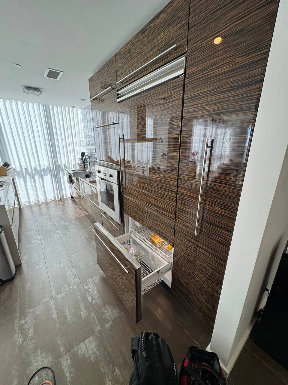 Built-in freezer drawer pulled out of a dark wood kitchen column with the baskets visible